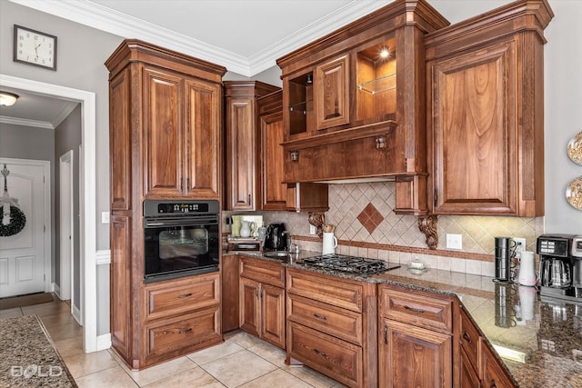 kitchen featuring decorative backsplash, dark stone countertops, crown molding, stainless steel gas cooktop, and black oven