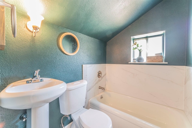 bathroom featuring a garden tub, lofted ceiling, a textured wall, toilet, and a textured ceiling