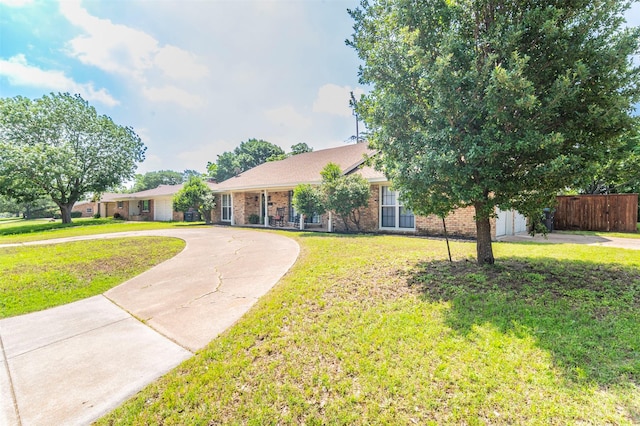 view of front of home featuring brick siding, fence, concrete driveway, and a front yard