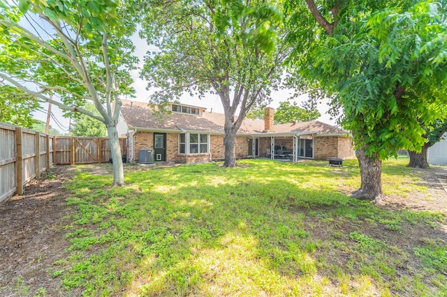 exterior space featuring brick siding, a chimney, a lawn, central AC, and a fenced backyard