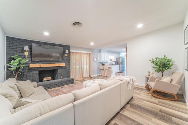 living room with recessed lighting, a fireplace, visible vents, and light wood-style floors