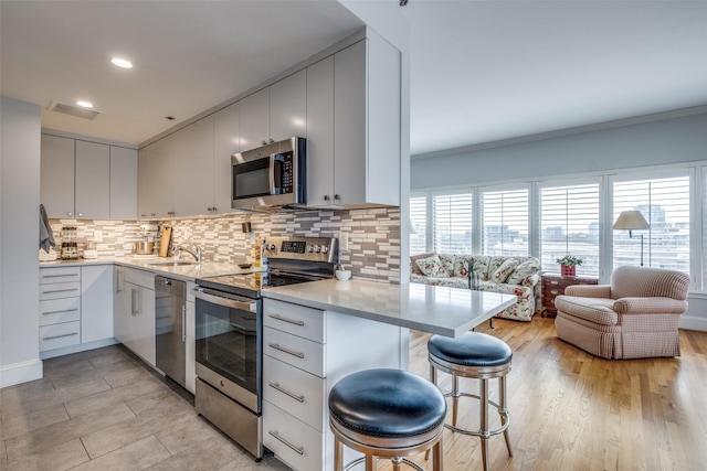 kitchen featuring a breakfast bar, white cabinetry, appliances with stainless steel finishes, and light countertops