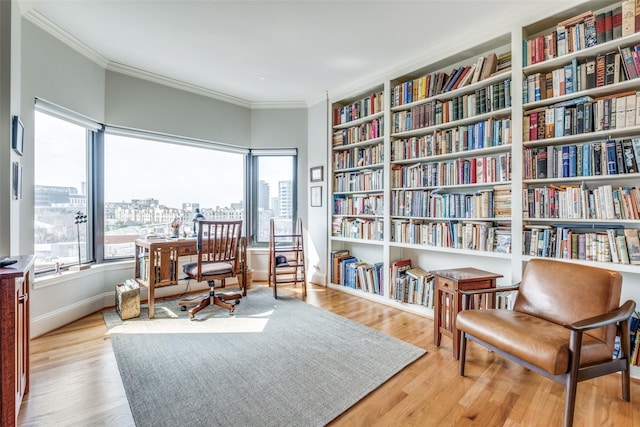 living area featuring baseboards, light wood-style flooring, crown molding, a city view, and built in shelves