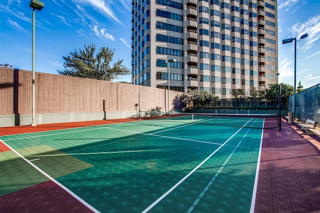 view of tennis court with community basketball court and fence