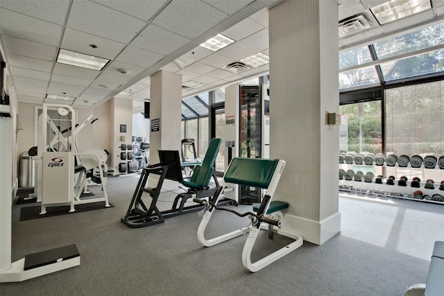 gym with a paneled ceiling, floor to ceiling windows, visible vents, and a wealth of natural light