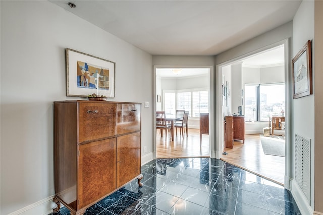 hallway featuring ornamental molding, marble finish floor, visible vents, and baseboards