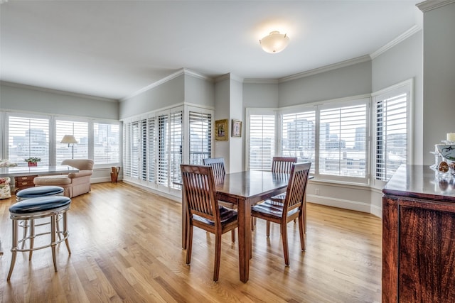 dining room with ornamental molding, light wood-style flooring, and baseboards