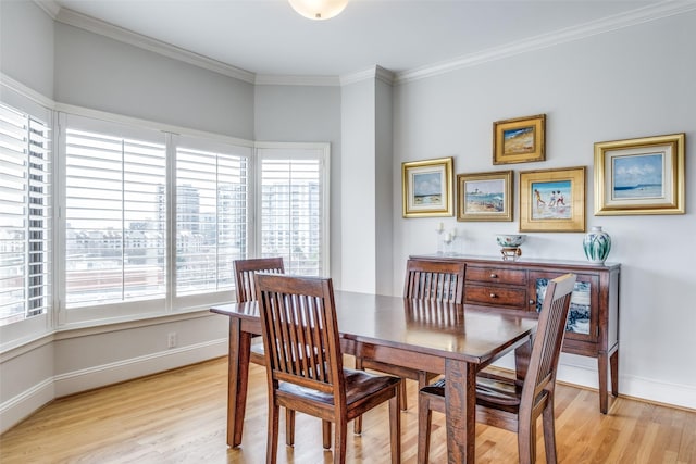 dining area featuring light wood finished floors, baseboards, and ornamental molding