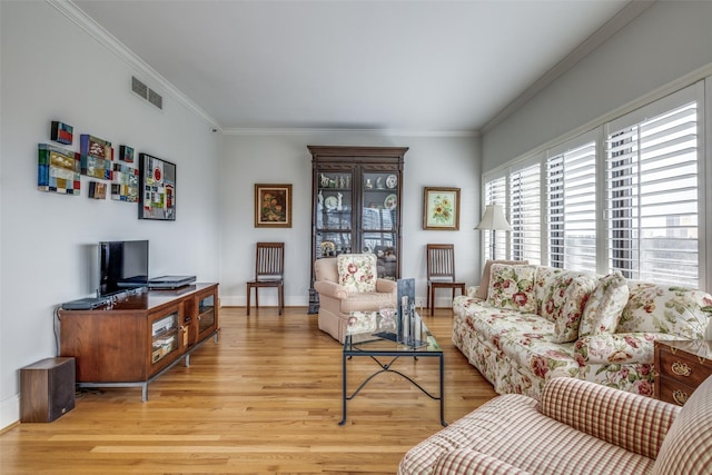 living area featuring ornamental molding, visible vents, light wood-style flooring, and baseboards