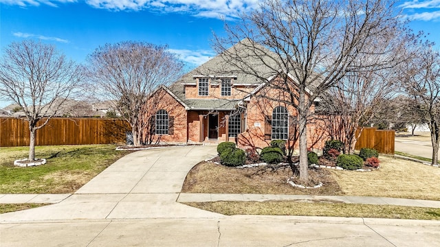 traditional-style house with brick siding, a shingled roof, fence, driveway, and stone siding