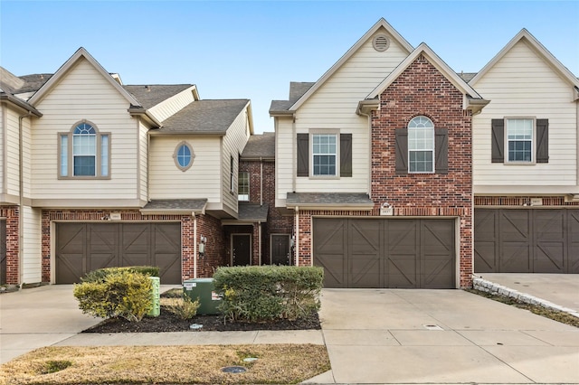 townhome / multi-family property featuring an attached garage, a shingled roof, concrete driveway, and brick siding