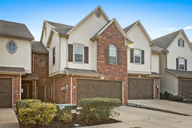 view of property with a shingled roof, brick siding, driveway, and an attached garage