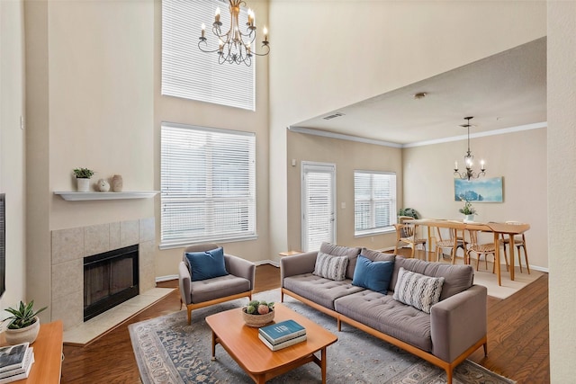 living room with a chandelier, a fireplace, wood finished floors, baseboards, and ornamental molding