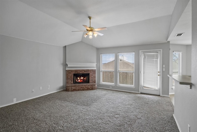 unfurnished living room featuring plenty of natural light, lofted ceiling, ceiling fan, carpet floors, and a brick fireplace