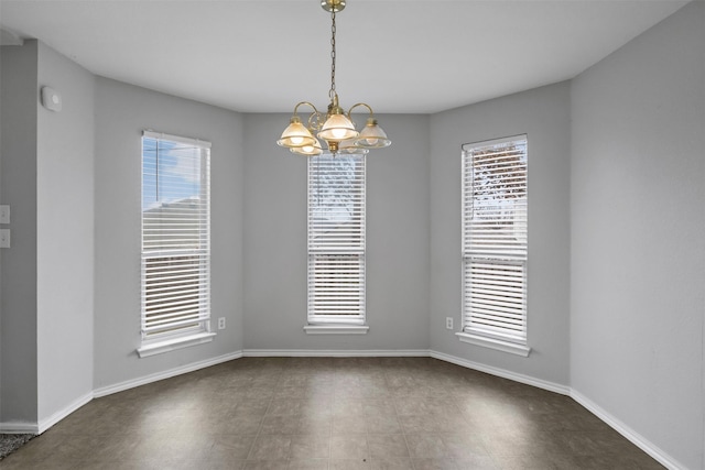 unfurnished dining area featuring baseboards and a chandelier