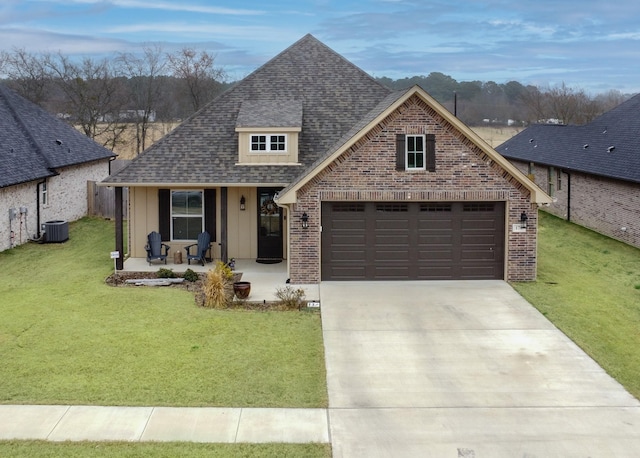 view of front of home featuring covered porch, roof with shingles, brick siding, and a front yard