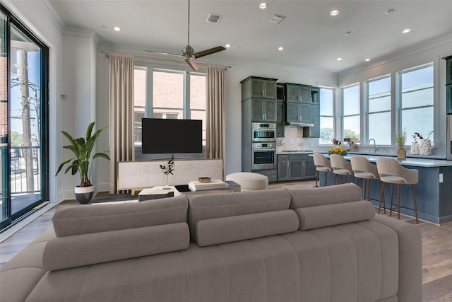 living area featuring plenty of natural light, visible vents, and ornamental molding