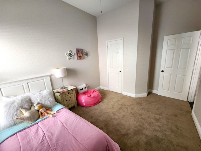 bedroom with a high ceiling, dark carpet, and baseboards