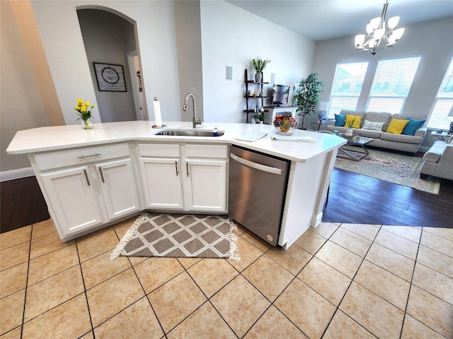 kitchen with decorative light fixtures, light countertops, stainless steel dishwasher, open floor plan, and a sink