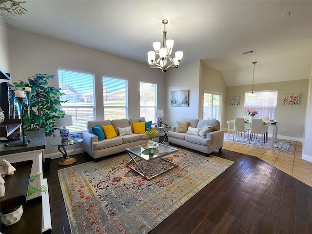 living area with a notable chandelier, wood finished floors, visible vents, baseboards, and vaulted ceiling