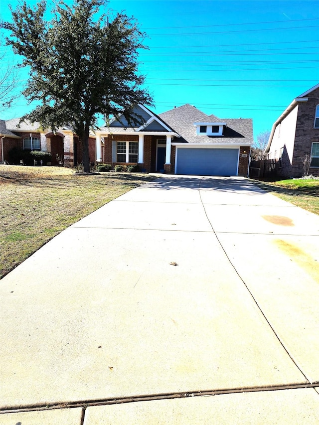 view of front of house with driveway, brick siding, an attached garage, and a front yard