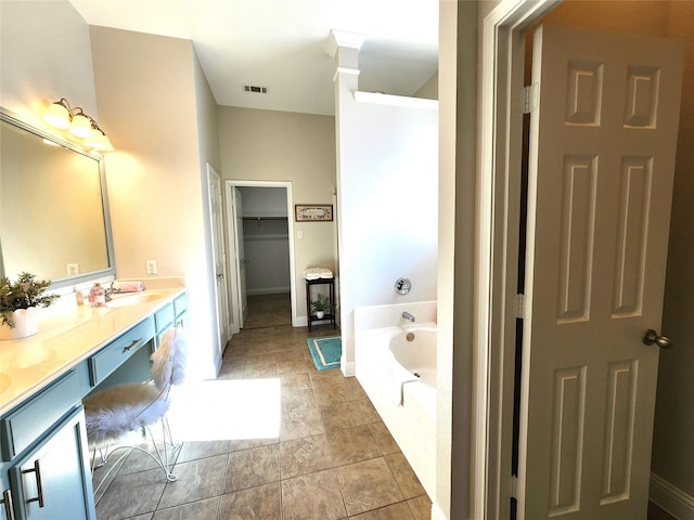 full bath with double vanity, visible vents, a garden tub, a walk in closet, and a sink