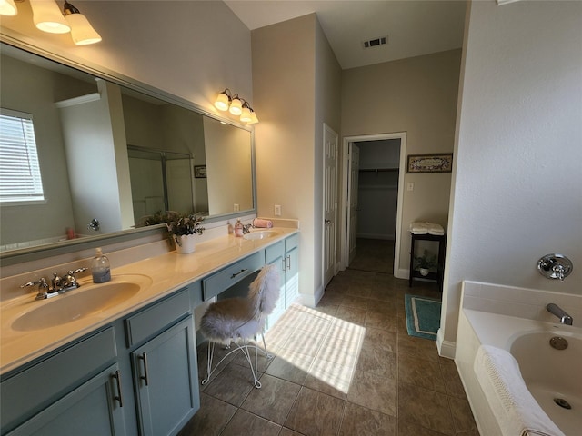 full bath with a garden tub, double vanity, visible vents, a spacious closet, and a sink