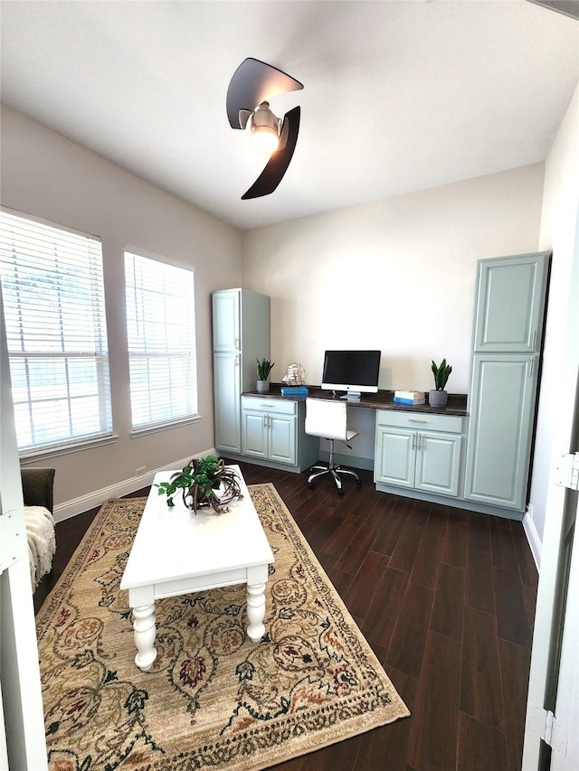 office space featuring a ceiling fan, baseboards, dark wood-style flooring, and built in study area