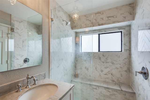 full bathroom featuring a textured wall, a tile shower, and vanity