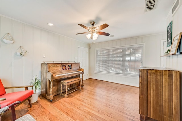 living area with light wood-style floors, visible vents, and ornamental molding