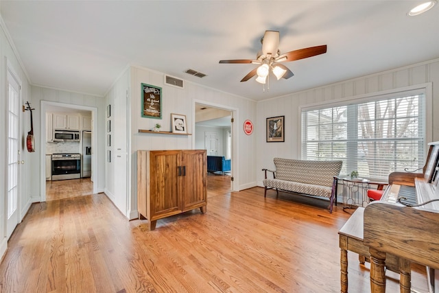 sitting room with a ceiling fan, light wood-type flooring, visible vents, and crown molding