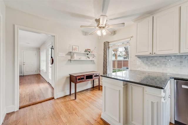 kitchen featuring light wood-style flooring, a ceiling fan, white cabinetry, tasteful backsplash, and dark stone countertops