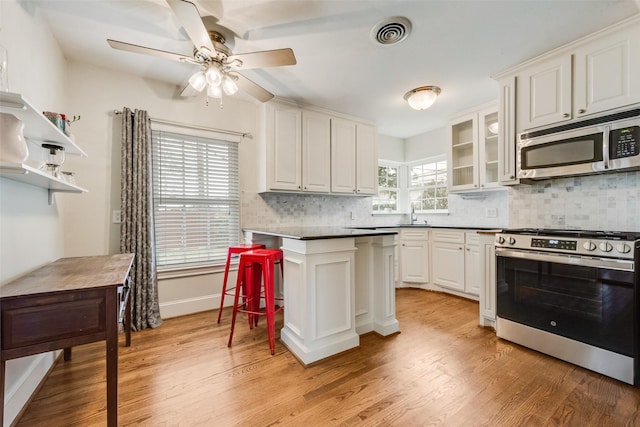 kitchen with appliances with stainless steel finishes, white cabinets, and glass insert cabinets