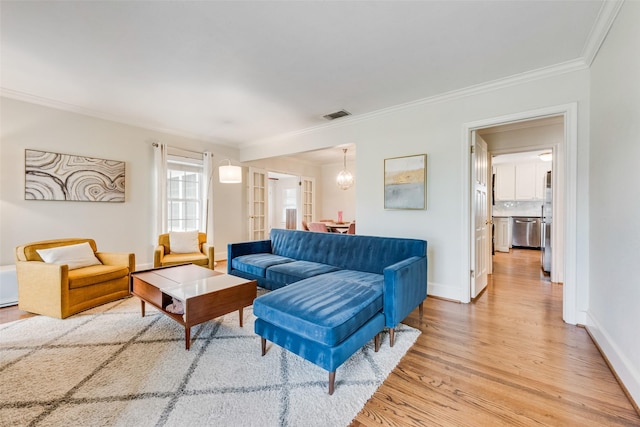 living area featuring light wood-style floors, visible vents, ornamental molding, and baseboards