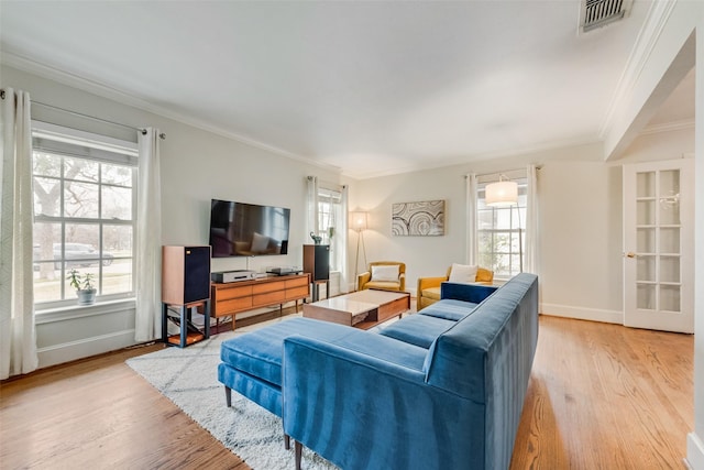 living area with plenty of natural light, light wood-style flooring, visible vents, and crown molding