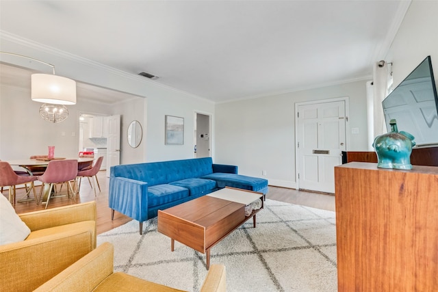 living area featuring ornamental molding, light wood-style flooring, visible vents, and baseboards