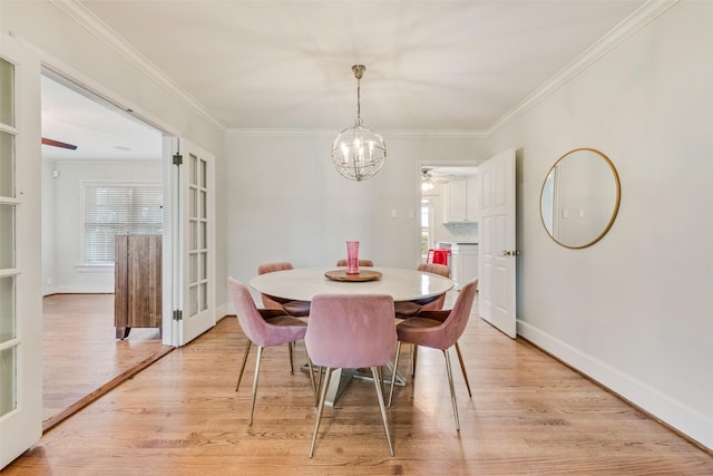 dining room featuring light wood-style flooring, ornamental molding, baseboards, and ceiling fan with notable chandelier