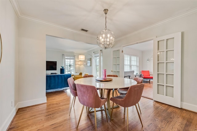 dining room with baseboards, visible vents, ornamental molding, wood finished floors, and a notable chandelier