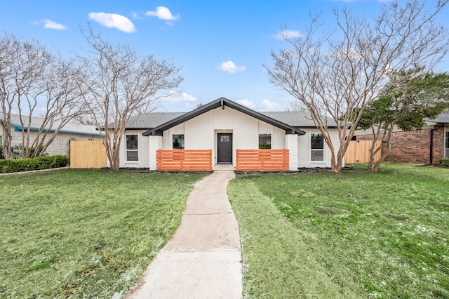 mid-century inspired home with brick siding, fence, and a front lawn