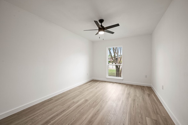 empty room with a ceiling fan, light wood-style flooring, and baseboards