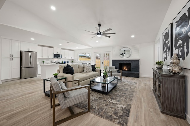 living area with light wood finished floors, recessed lighting, a ceiling fan, a brick fireplace, and vaulted ceiling