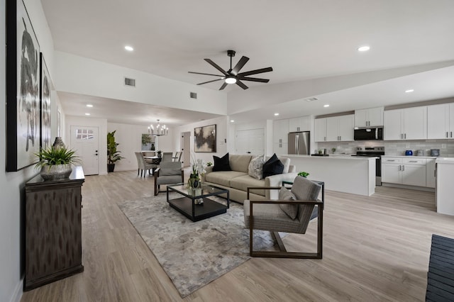 living room featuring light wood finished floors, visible vents, lofted ceiling, ceiling fan with notable chandelier, and recessed lighting