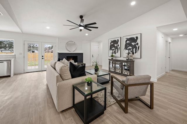 living area featuring recessed lighting, light wood-style floors, vaulted ceiling, french doors, and a brick fireplace