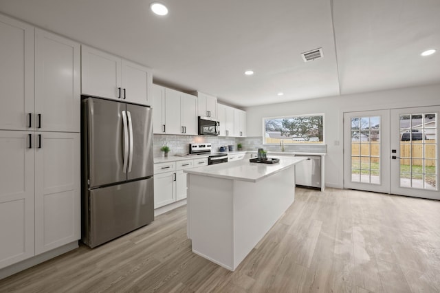 kitchen featuring a center island, light countertops, backsplash, appliances with stainless steel finishes, and white cabinetry