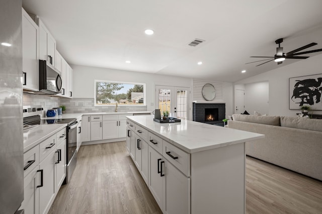 kitchen with visible vents, white cabinets, appliances with stainless steel finishes, open floor plan, and a center island