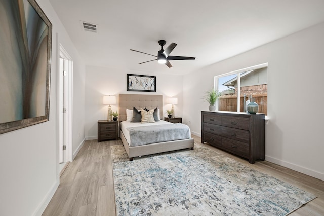 bedroom with light wood-type flooring, visible vents, ceiling fan, and baseboards