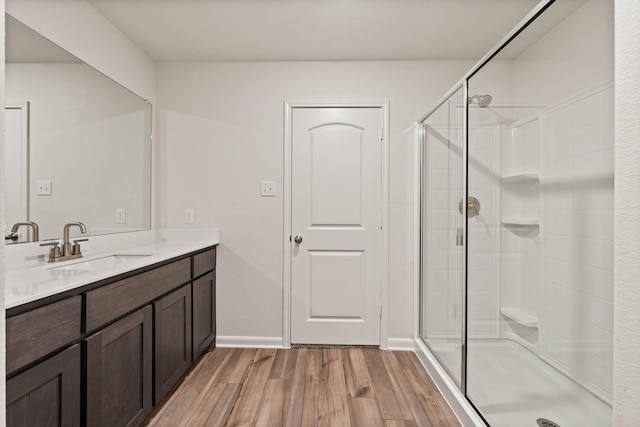 bathroom with a stall shower, baseboards, wood finished floors, and vanity