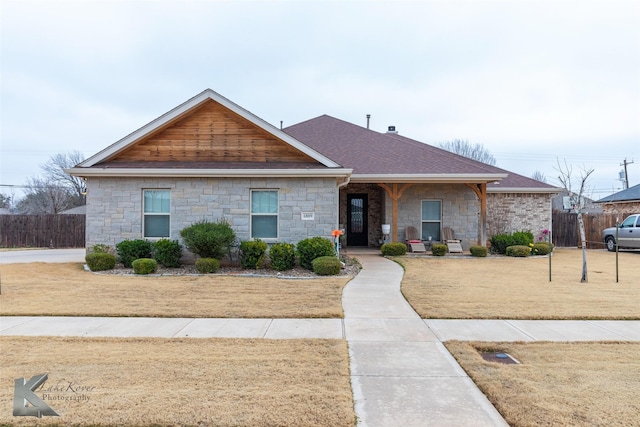 view of front of house with a front yard, roof with shingles, and fence