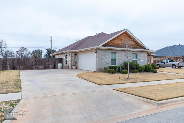 view of front of property featuring an attached garage, a shingled roof, fence, and concrete driveway