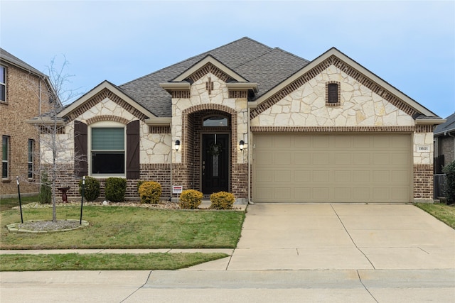 french country style house featuring an attached garage, brick siding, a shingled roof, concrete driveway, and a front yard